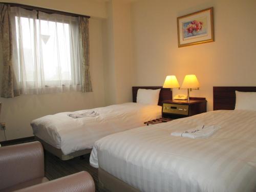 a hotel room with two beds and a window at Hotel Green With in Sendai