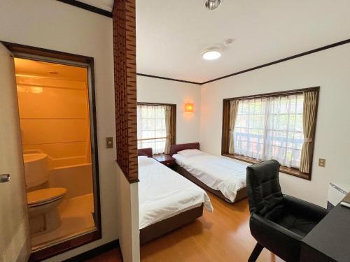 een slaapkamer met 2 bedden en een badkamer met een toilet bij Norikura Kogen - irodori - - Vacation STAY 91520v in Matsumoto