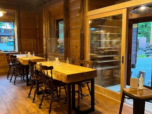 een eetkamer met houten tafels, stoelen en ramen bij Norikura Kogen - irodori - - Vacation STAY 91520v in Matsumoto