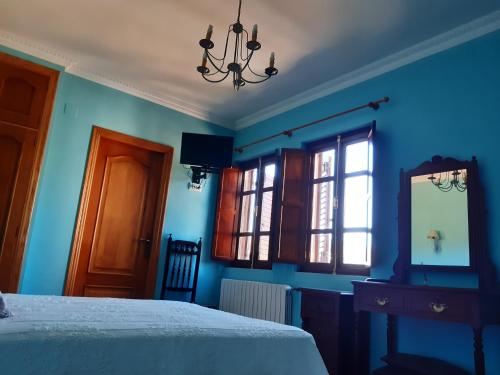 a bedroom with blue walls and a bed and a mirror at Casa Rural dos Chaos in Arnoia
