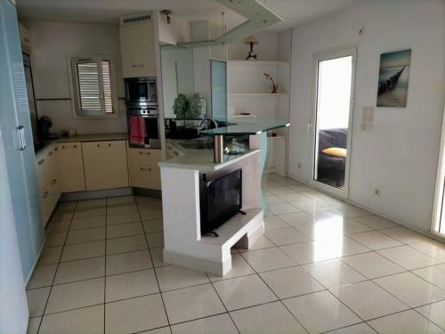 a kitchen with a tv on a tiled floor at Bel appartement avec piscine, face à la mer in Gourbeyre