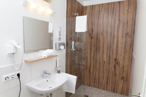 a white bathroom with a sink and a shower at Hotel Hohenloher Tor in Bretzfeld