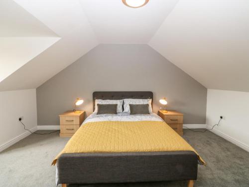 a attic bedroom with a bed and two night stands at Yr Hen Efail in Cemaes Bay