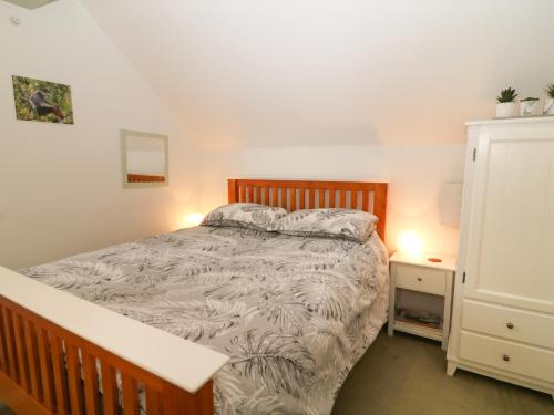 a bedroom with a bed and a dresser with a night stand at Awdry Bungalow in Beaworthy