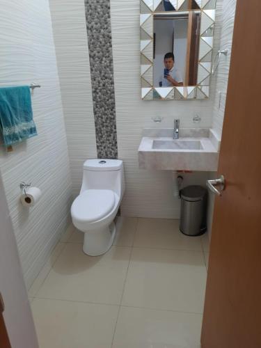 a bathroom with a toilet and a sink and a mirror at Departamento Moderno Alberca Compartida - 6 Personas in Mazatlán