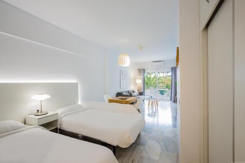 Apartamento Blanco 127 en La Caleta - Altamira في أديخي: غرفة نوم بسريرين وصالة جلوس