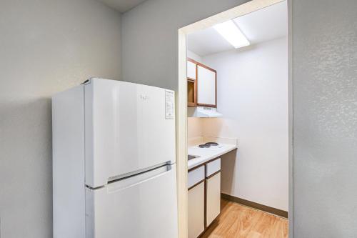 a kitchen with a white refrigerator and a sink at HomeTowne Studios by Red Roof Atlanta – Lawrenceville in Lawrenceville