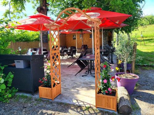 un patio con una sombrilla roja y algunas plantas en hotel de la gare, en Verchamp