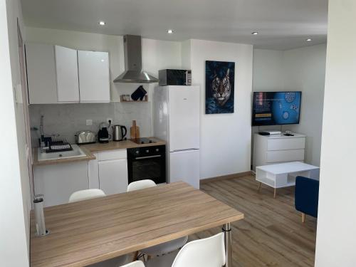 une cuisine avec une table, des chaises et un réfrigérateur dans l'établissement La Maison 19 : Studio 2 personnes Louvre Lens, à Lens