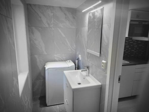 a white bathroom with a sink and a refrigerator at Nesttunveien appartments in Bergen