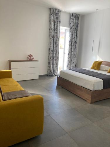 1 dormitorio con 2 camas y sofá amarillo en La Casa al Gelso en Rodi Garganico