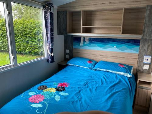 um quarto com uma cama com um edredão azul e uma janela em Blackpool caravans Marton mere em Blackpool