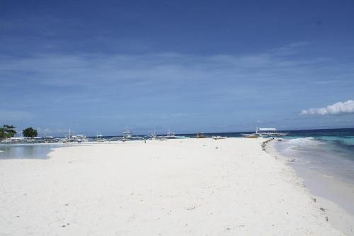 a beach with white sand and the ocean at Liwayway sa Bohol Pamilacan Resort in Baclayon