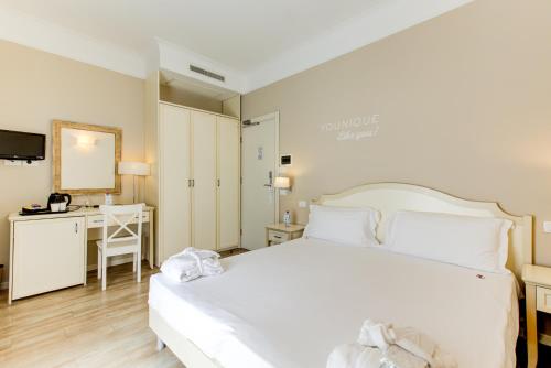 a bedroom with a large white bed and a desk at BeYou Hotel Villa Rosa in Riccione