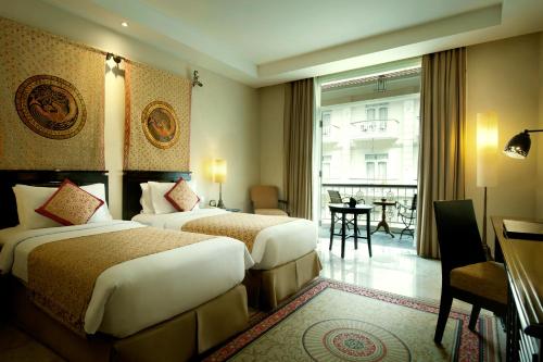 The Phoenix Hotel Yogyakarta - MGallery Collection tesisinde bir odada yatak veya yataklar