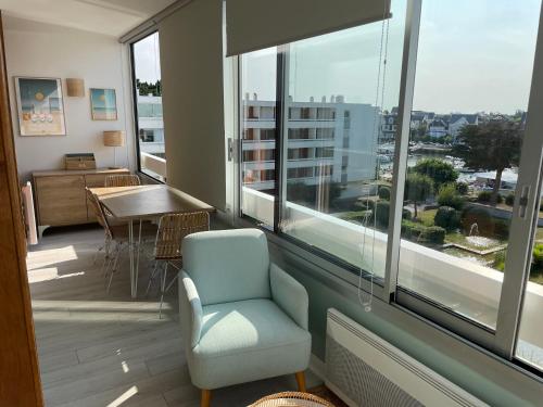 une chambre avec une chaise, une table et des fenêtres dans l'établissement Appartement de standing, vue sur port de plaisance, à La Baule