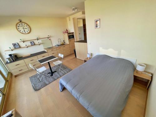 - une chambre avec un lit, un bureau et une horloge dans l'établissement #901 MARINA RIVIERA BAY - Studio vue Mer et Port Panoramique, à Villeneuve-Loubet