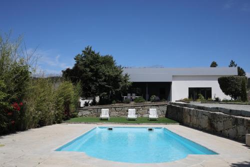 una piscina con 2 sillas y una casa en Casa dos Remendos - Alojamento Local en Termas de Sao Pedro do Sul