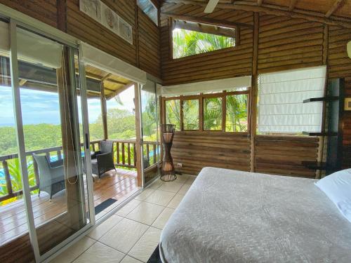 een slaapkamer met een bed en een balkon met ramen bij Horizon Hotel & Yoga center in Santa Teresa Beach