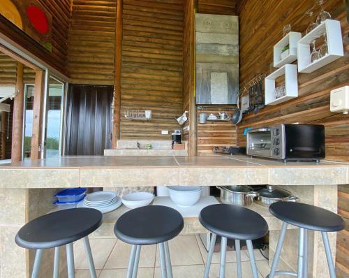 a kitchen with four bar stools and a counter at Horizon Hotel & Yoga Center in Santa Teresa Beach