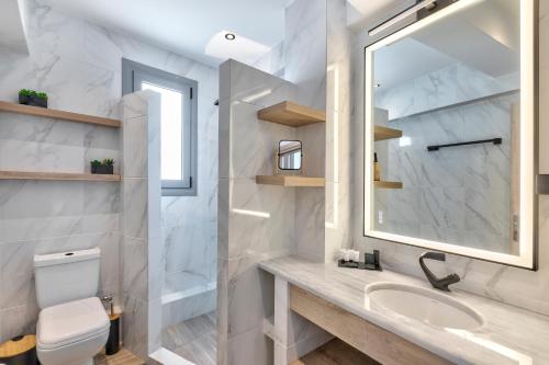 ein weißes Badezimmer mit Waschbecken und Spiegel in der Unterkunft Acropolis City Life BH in Athen