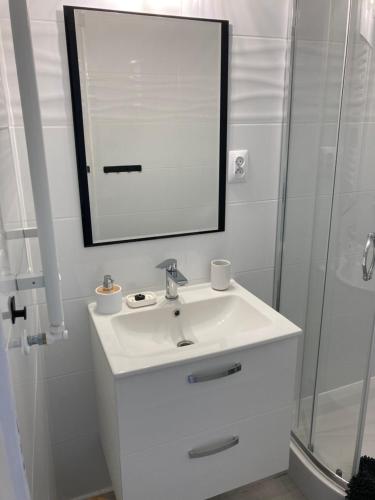 W białej łazience znajduje się umywalka i lustro. w obiekcie Kamienica nad Maltą- Studio przy Malcie w Poznaniu