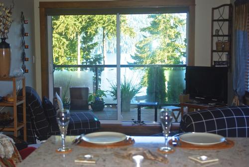 a living room with a table and a large window at Wild Coast Chalets in Port Renfrew
