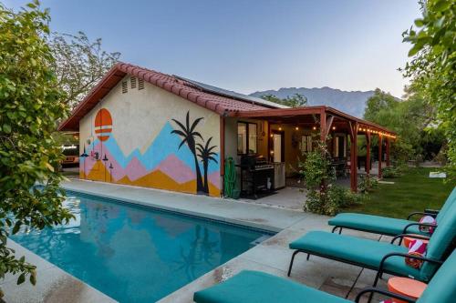 a house with a swimming pool with chairs next to it at Poolside Palm Springs Paradise in Palm Springs