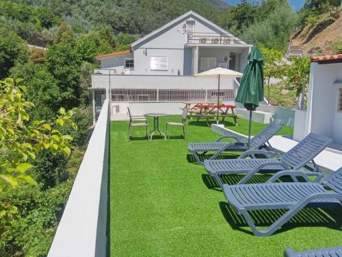 a row of chairs and an umbrella on a lawn at Atlantico in Geres