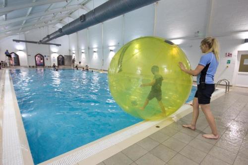 a woman standing next to a large ball in a swimming pool at Blue Bay View - One Bed Apartment @ The Bay, Filey in Reighton