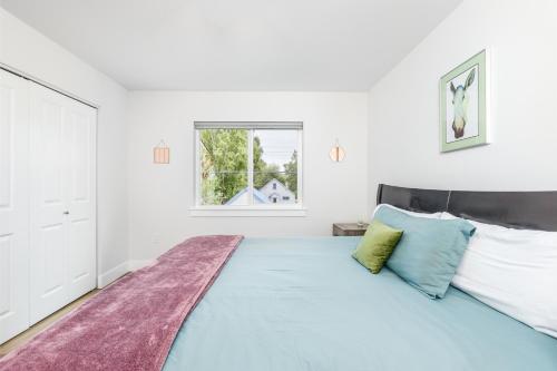 a white bedroom with a large bed with blue pillows at Downtown Getaway in Anchorage