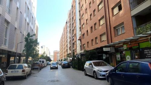een drukke stadsstraat met geparkeerde auto's en gebouwen bij Jeta Apartment in Pristina
