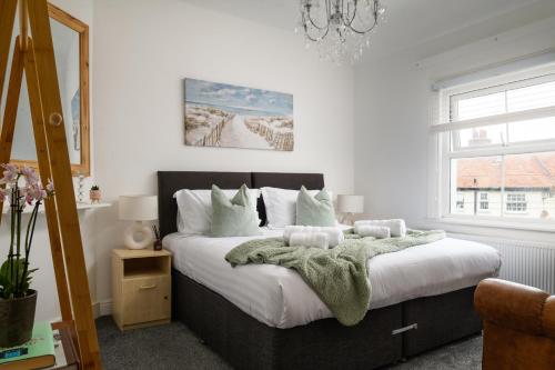 a bedroom with a bed with a green blanket on it at Modern, light and airy townhouse in Llandudno, West Shore in Llandudno