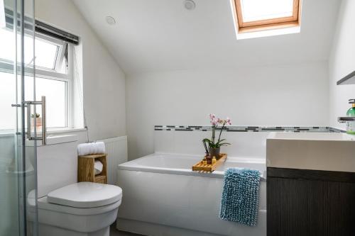 a bathroom with a tub and a toilet and a sink at Modern, light and airy townhouse in Llandudno, West Shore in Llandudno
