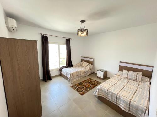 a bedroom with two beds and a window at Amwaj Seaside Retreat- Luxury 2BR Chalet in Amwaj Sidi Abdelrahman in El Alamein