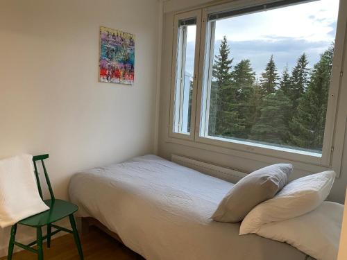 a bedroom with a bed and a window with a chair at Moderni ullakkohuoneisto in Kuopio