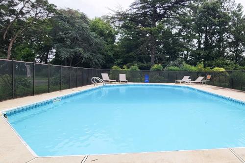 a large blue swimming pool with two chairs and a fence at Bayfront Retreat with Game Room and Outdoor Pool! in Exmore