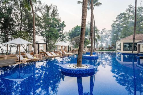 a pool at a resort with a palm tree in the middle at Silver Waves Resort & Spa Daman, a member of Radisson Individuals in Daman