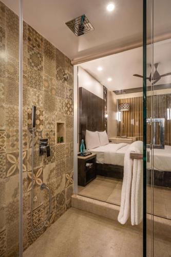 a bathroom with a shower and a bed in a room at Silver Waves Resort & Spa - Daman in Daman
