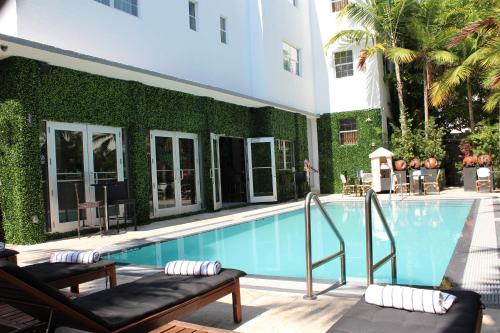 una piscina con 2 tumbonas junto a un edificio en San Juan Hotel Miami Beach, en Miami Beach