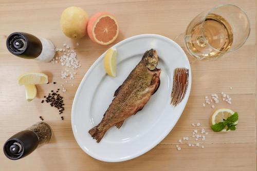 a fish on a plate with a glass of wine at Wrzos & Belvedere in Kudowa-Zdrój