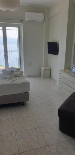 sypialnia z łóżkiem i telewizorem oraz podłogą wyłożoną kafelkami w obiekcie Beachfront Houses w mieście Pogoniá