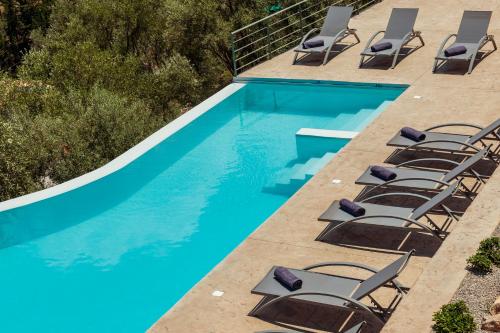 a swimming pool with lounge chairs next to it at Mylos Mountain Villas- Villa Giorgio in Agios Nikitas