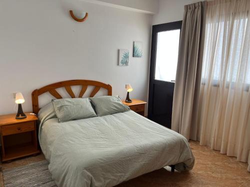a bedroom with a bed with two lamps and a window at Apartamento Playa Honda in Playa Honda
