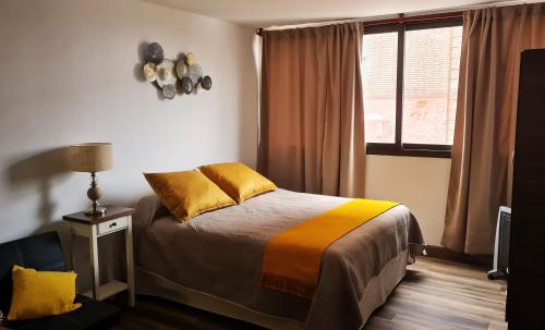 een slaapkamer met een bed met gele kussens en een raam bij Departamento a metros de la Peatonal in Mendoza