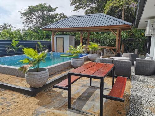 um quintal com uma piscina, uma mesa e um gazebo em Tropical appartement em Paramaribo