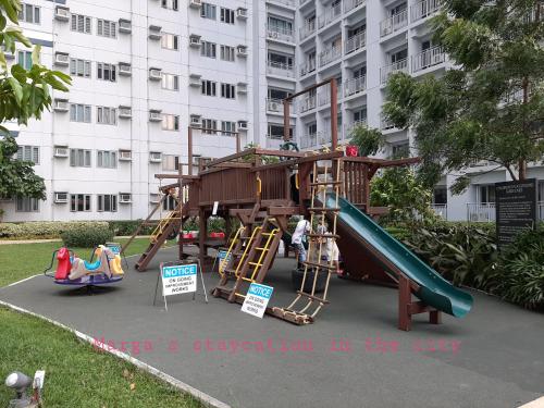 un parque infantil frente a un edificio con tobogán en Marga's staycation in the city en Manila