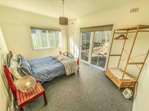 una camera da letto con un letto, una sedia e una finestra di Mount Beauty 3BR Home a Mount Beauty