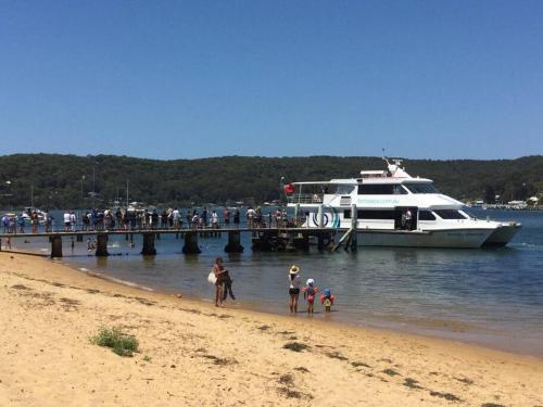 a boat docked at a pier with people walking on the beach at Cosy Cottage near the beach in Booker Bay