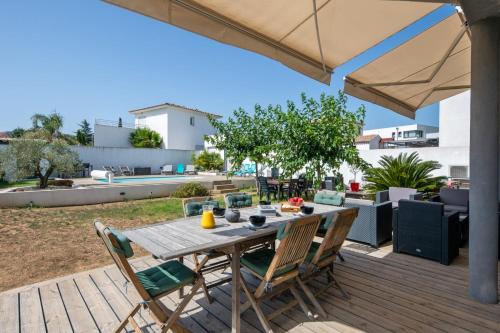 drewniany stół z krzesłami i parasol na tarasie w obiekcie Maison Janas - Welkeys w mieście La Seyne-sur-Mer